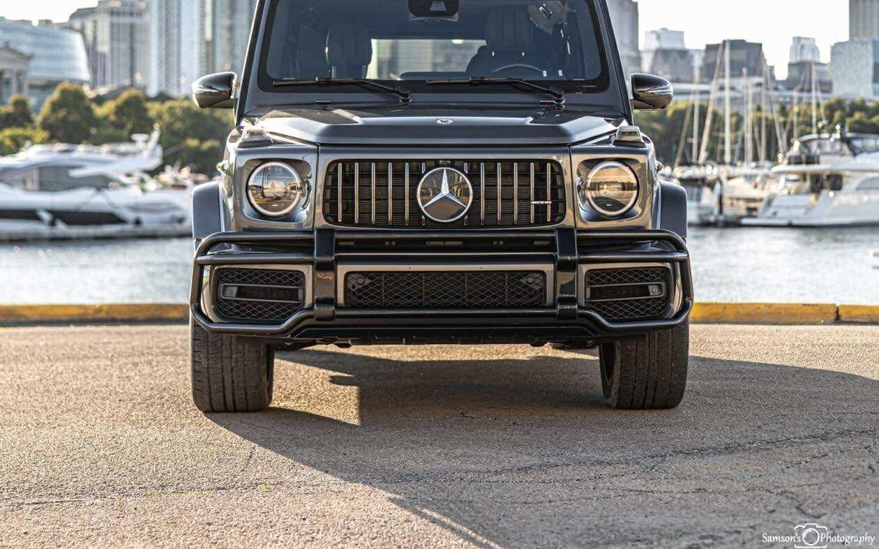 Graphite gray Mercedes-AMG G63 rental by a Chicago harbor with the skyline behind