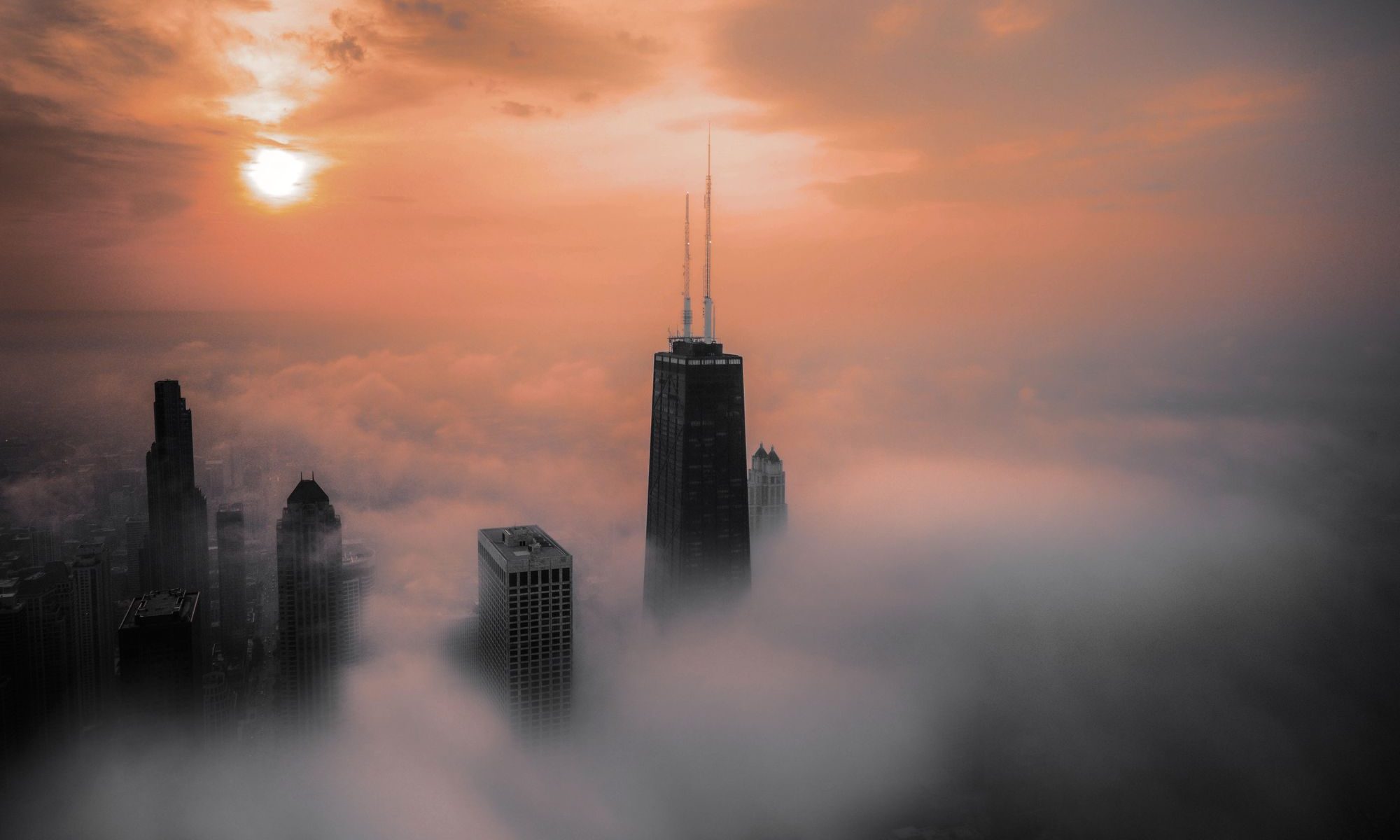 The John Hancock Center rising out of fog at sunset